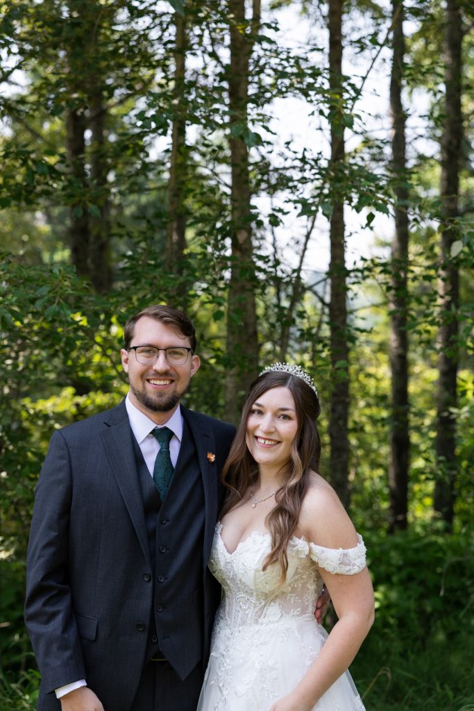 Newly married couple smiles for wedding photography in a wooded setting near Hayward, Wisconsin, showcasing