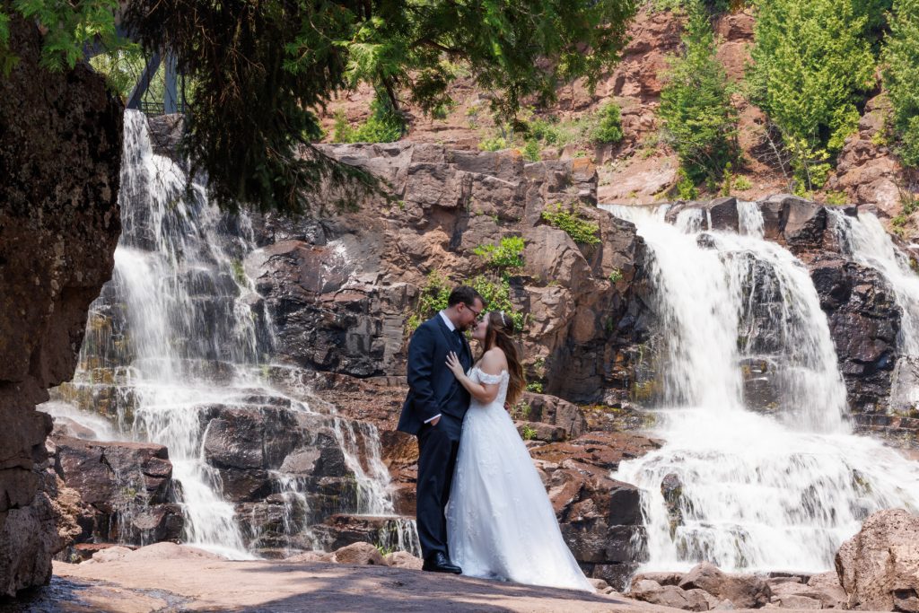 Bride and groom embrace tenderly near a cascading waterfall, captured by Beau Petersen Photography