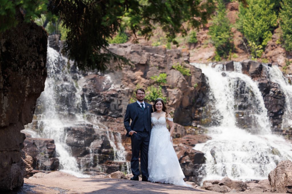 Newly married couple posing for wedding photography near a scenic waterfall in Wisconsin and Minnesota