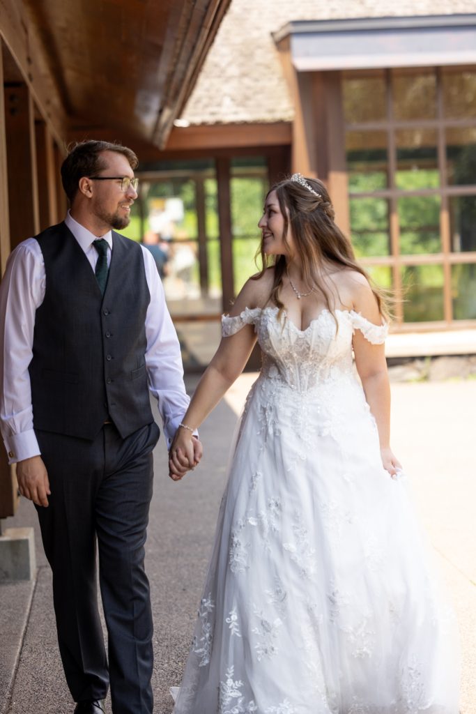 Newly married couple, holding hands and walking together, showcasing wedding photography in Hayward, Wisconsin