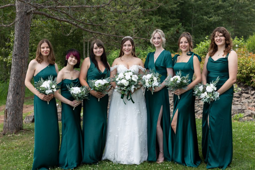 Bride and bridesmaids in emerald green dresses pose with bouquets at a Wisconsin wedding, captured