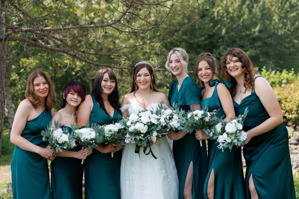 Bride and her bridesmaids in teal dresses pose with bouquets at a Wisconsin wedding, showcasing
