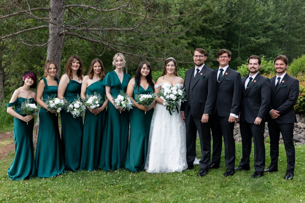 Bride and wedding party posing for a group photograph in Wisconsin, featuring bridesmaids in emerald