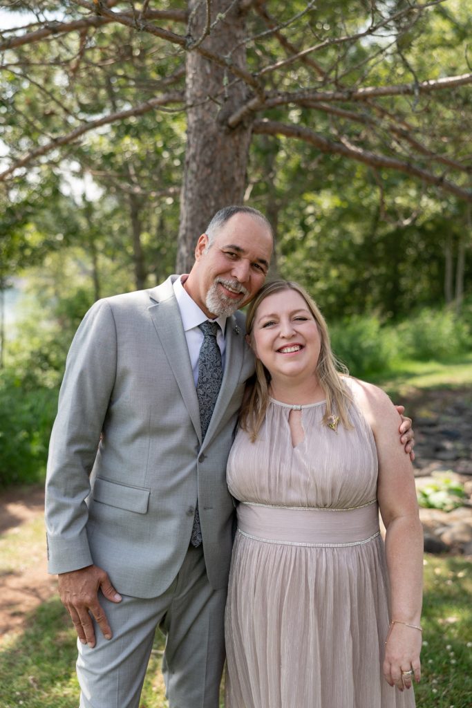 Couple embracing warmly outdoors, showcasing wedding attire and joyful expressions, captured by Beau Petersen Photography