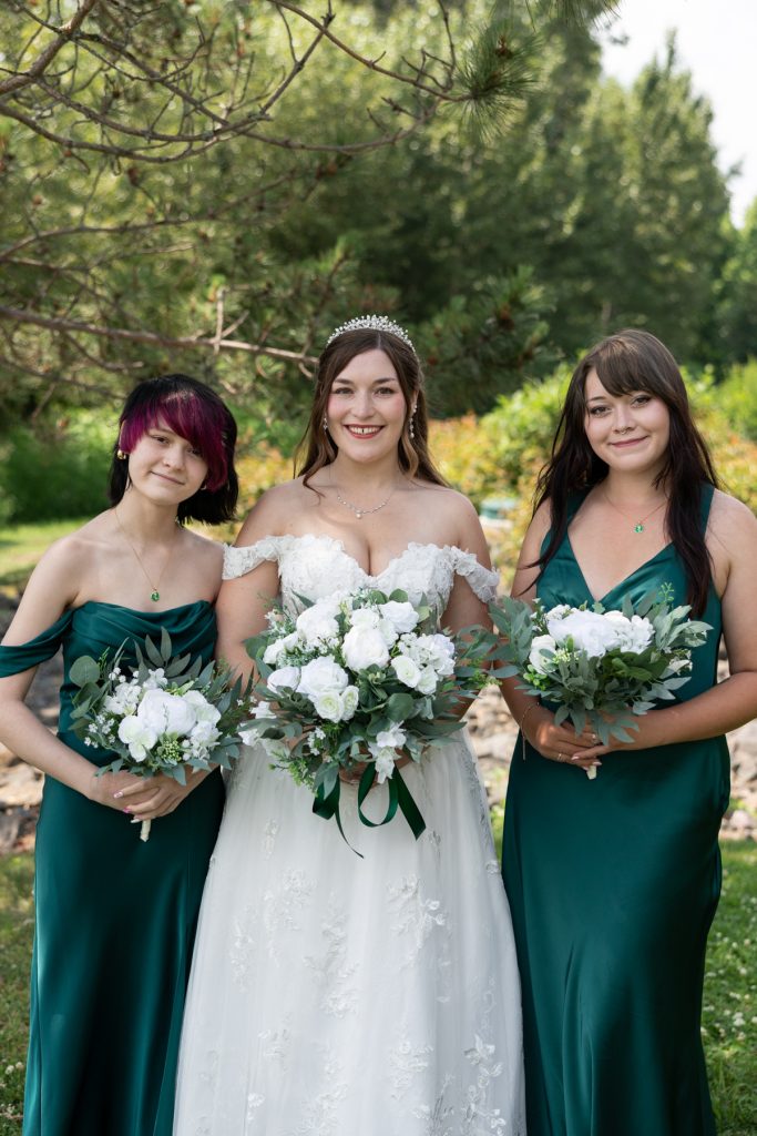 Bride with bridesmaids holding bouquets in a Wisconsin wedding, showcasing elegant green dresses and white