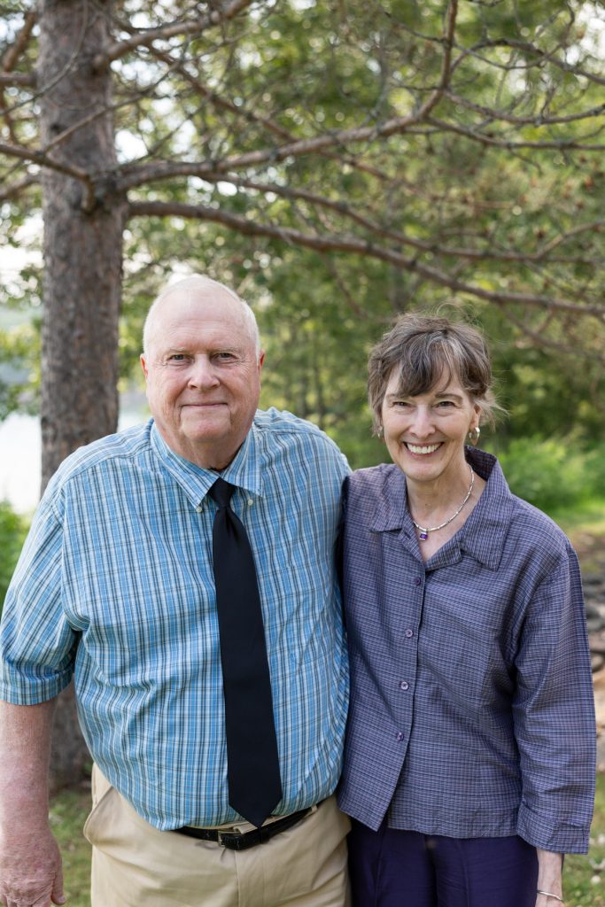 Couple smiling and posing for a wedding photography portrait in a wooded area