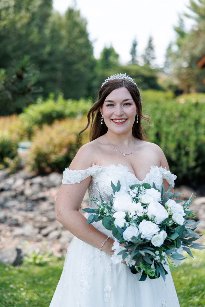 Bride in off-the-shoulder wedding gown holding a beautiful bouquet of white flowers, captured by Beau