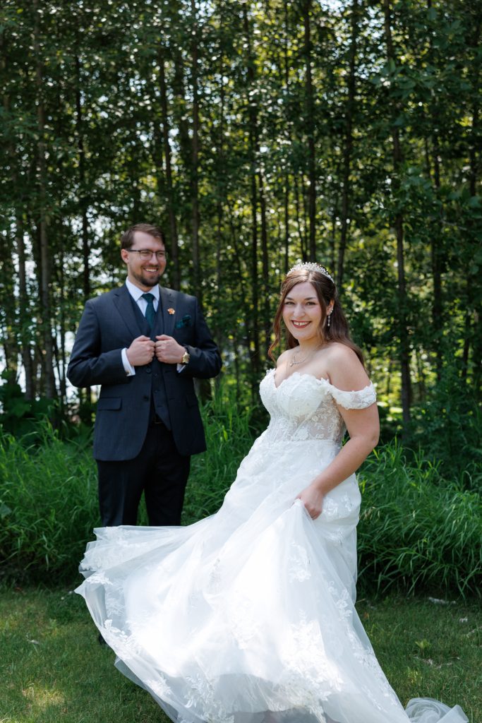 Bride and groom in wedding attire smiling and posing in a wooded area
