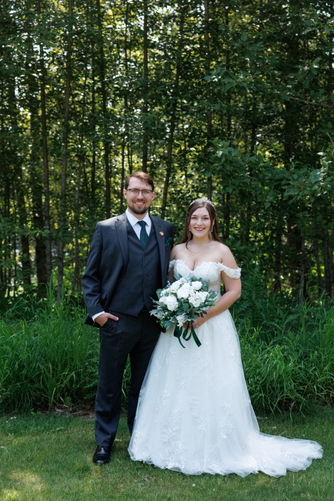 Newly married couple posing for wedding photography in a wooded area near Hayward, Wisconsin, showcasing