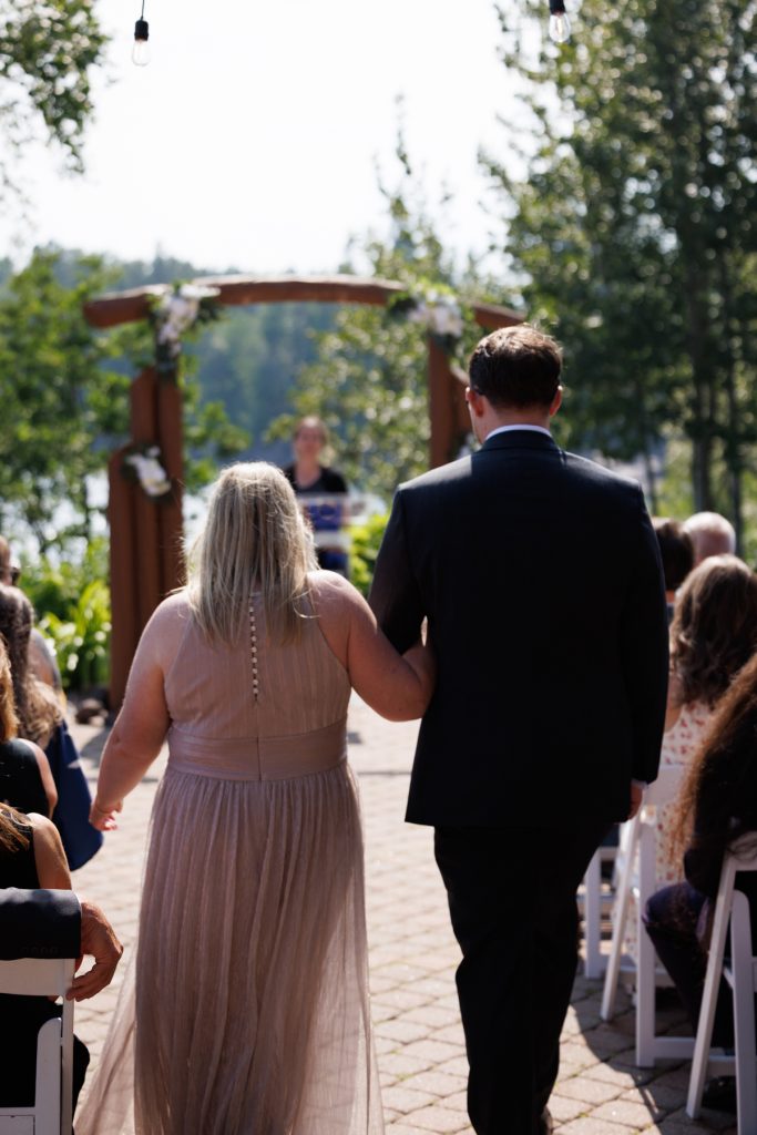 Bride and groom holding hands walking down the aisle toward a wooden arch