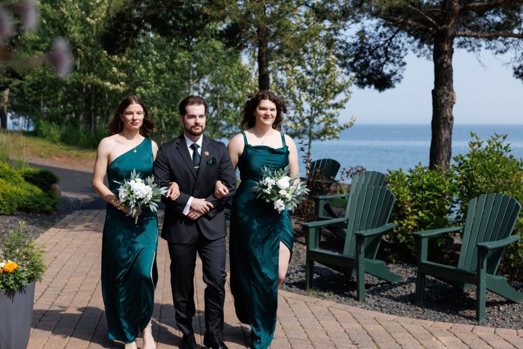 Wedding party walking along a pathway with a lake view in Hayward, Wisconsin, featuring bridesmaids