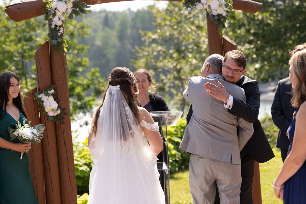 Bride and groom share a heartfelt moment with her father at a Wisconsin wedding ceremony