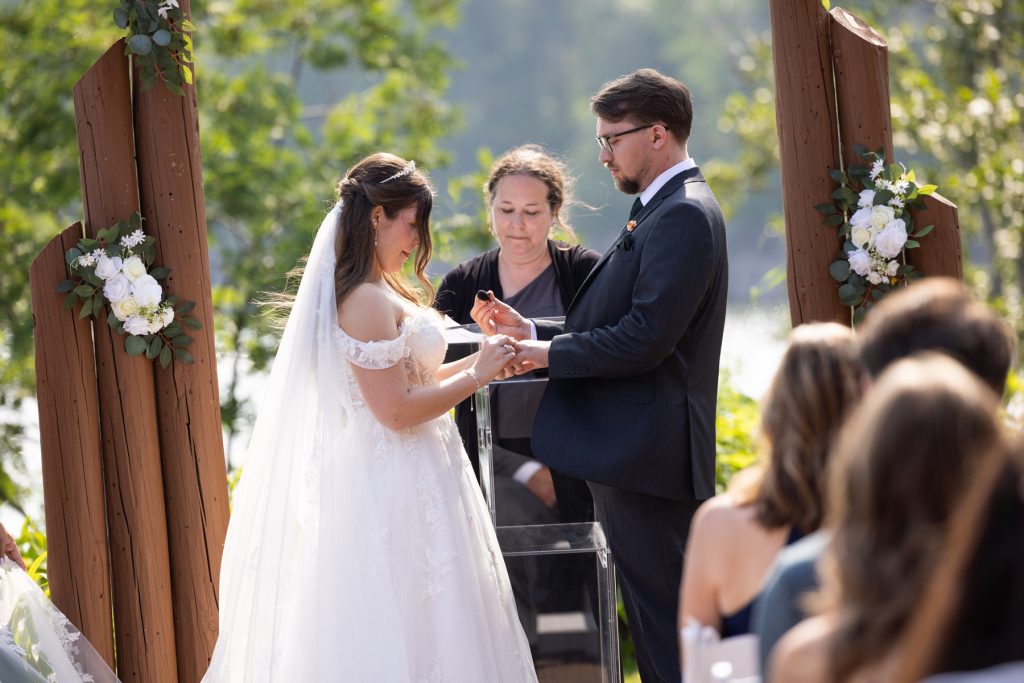 Bride and groom exchanging wedding rings during an outdoor ceremony in Hayward, Wisconsin, captured