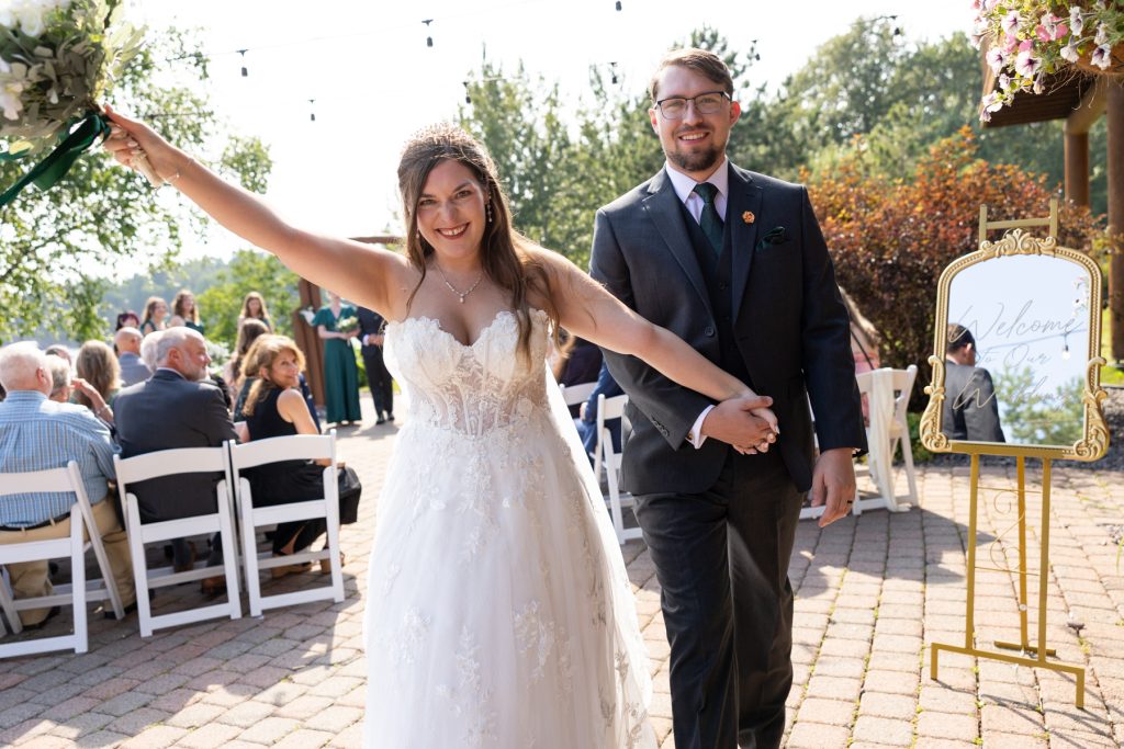 Newly married couple joyfully walking hand-in-hand through their wedding ceremony in Hayward, Wisconsin, celebrating