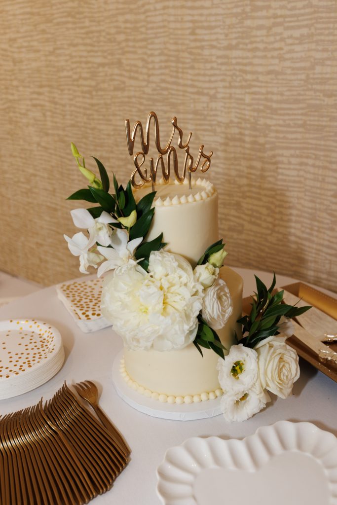 Elegant wedding cake with "Mr. & Mrs." topper and fresh white floral decorations, captured