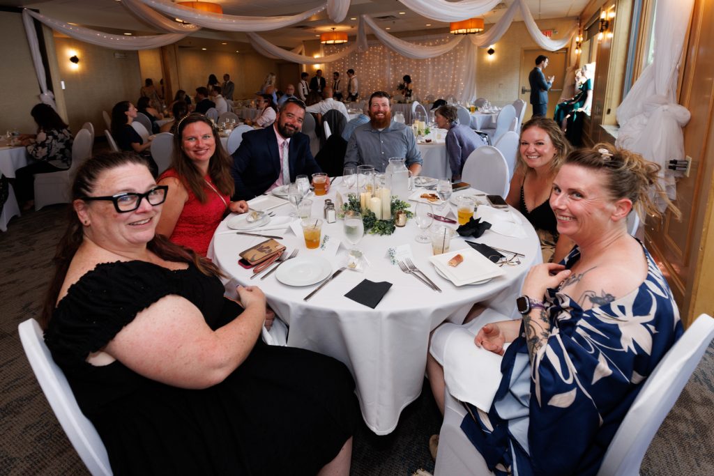 Group of wedding guests smiling and celebrating at a reception table in Wisconsin, captured