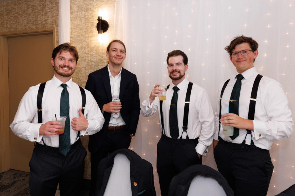 Four groomsmen in formal attire smiling at a Wisconsin wedding reception, showcasing Beau Petersen Photography's
