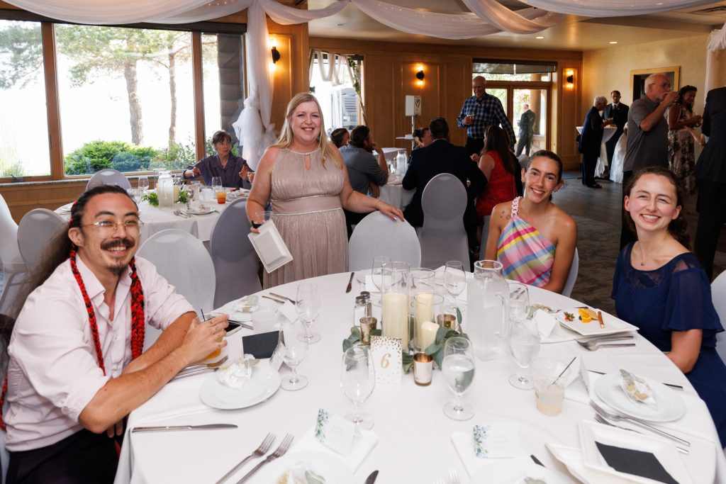 Wedding reception scene in Wisconsin featuring a group of smiling guests gathered around a beautifully