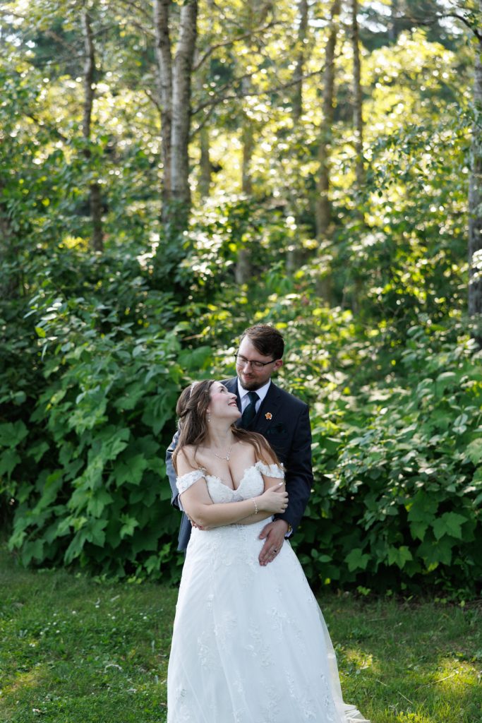 Newly married couple embracing in a lush forest setting, captured by Beau Petersen Photography, showcasing