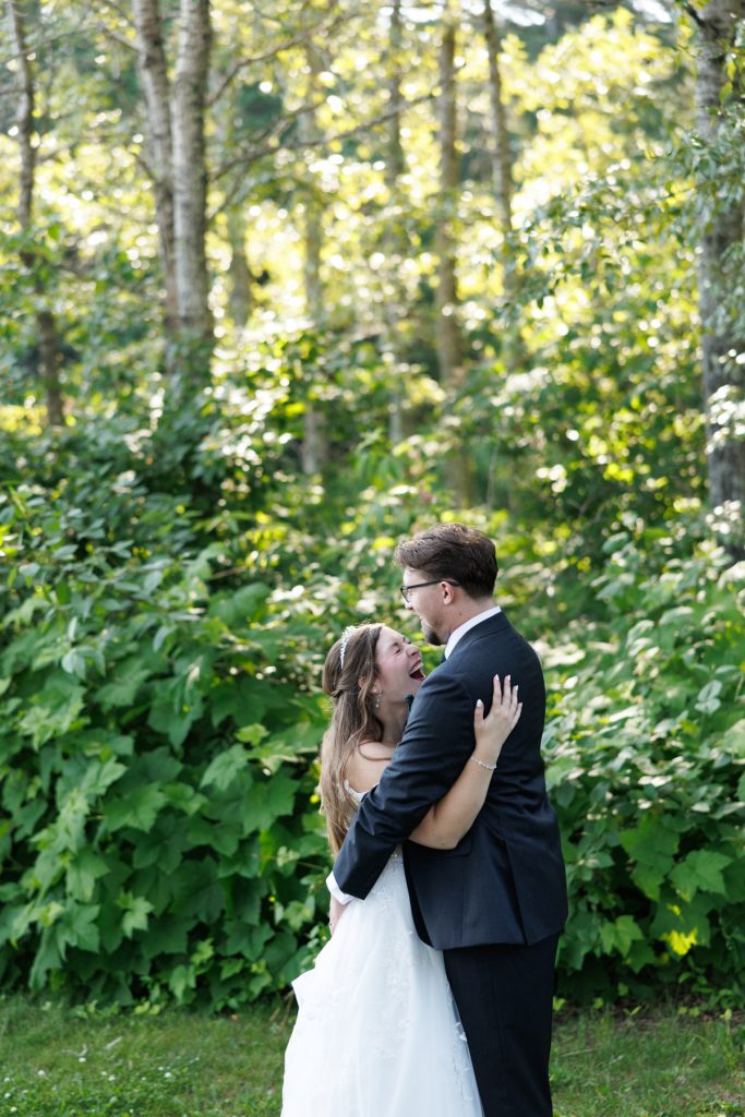 Bride and groom sharing a joyful first kiss surrounded by lush greenery, capturing a romantic