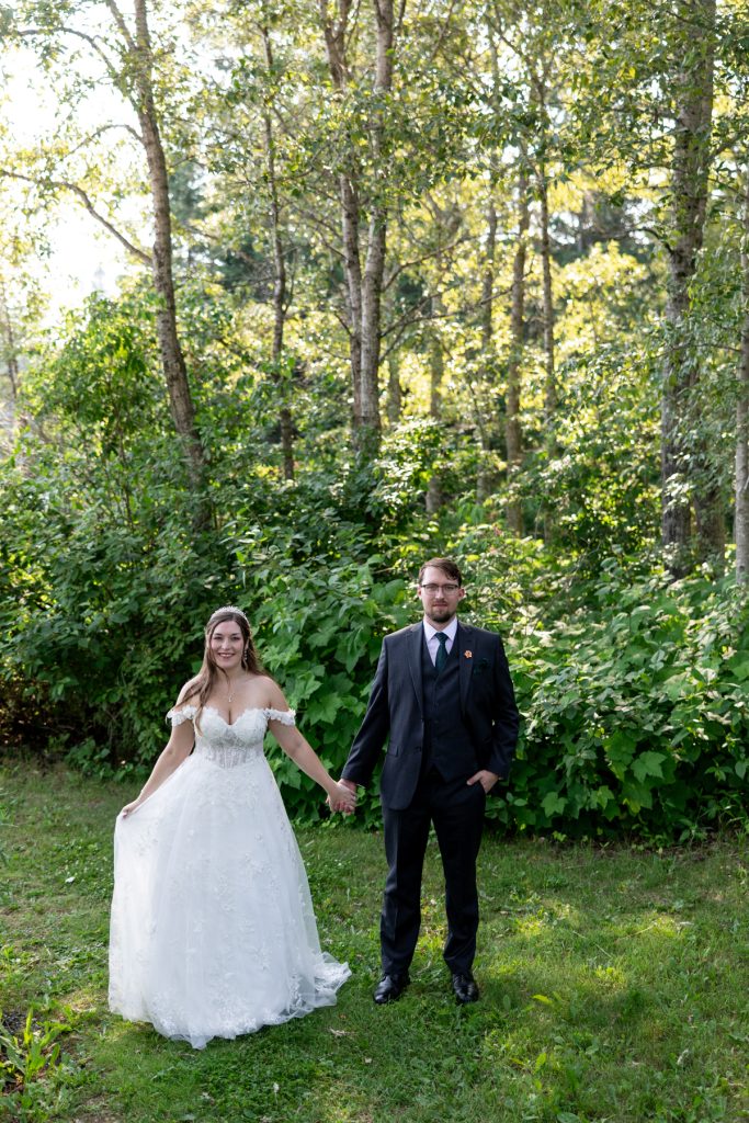 Newly married couple holding hands in a wooded setting, showcasing Wisconsin wedding photography and videography