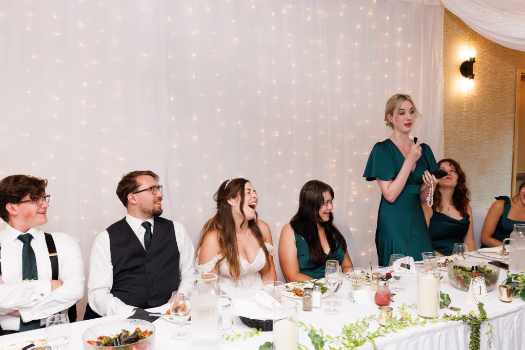 Bride's bridesmaid giving a speech at a wedding reception in Hayward, Wisconsin, with guests laughing
