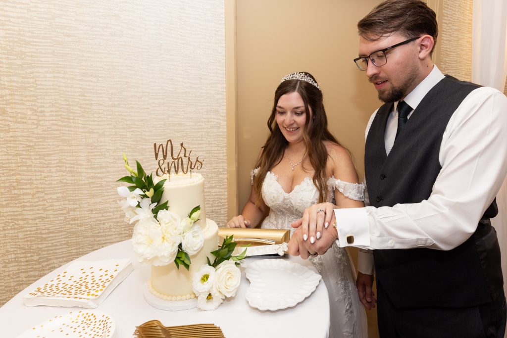 Newly married couple cutting a wedding cake adorned with "Mr. & Mrs." cake topper