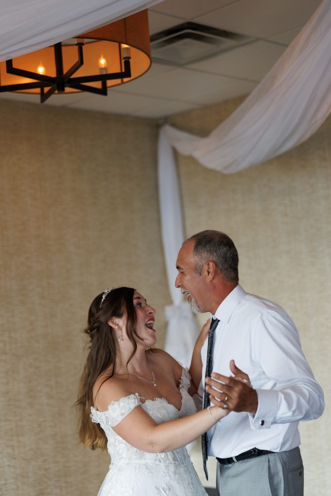 Bride and groom’s father laughing and dancing together at a Wisconsin wedding reception, captured