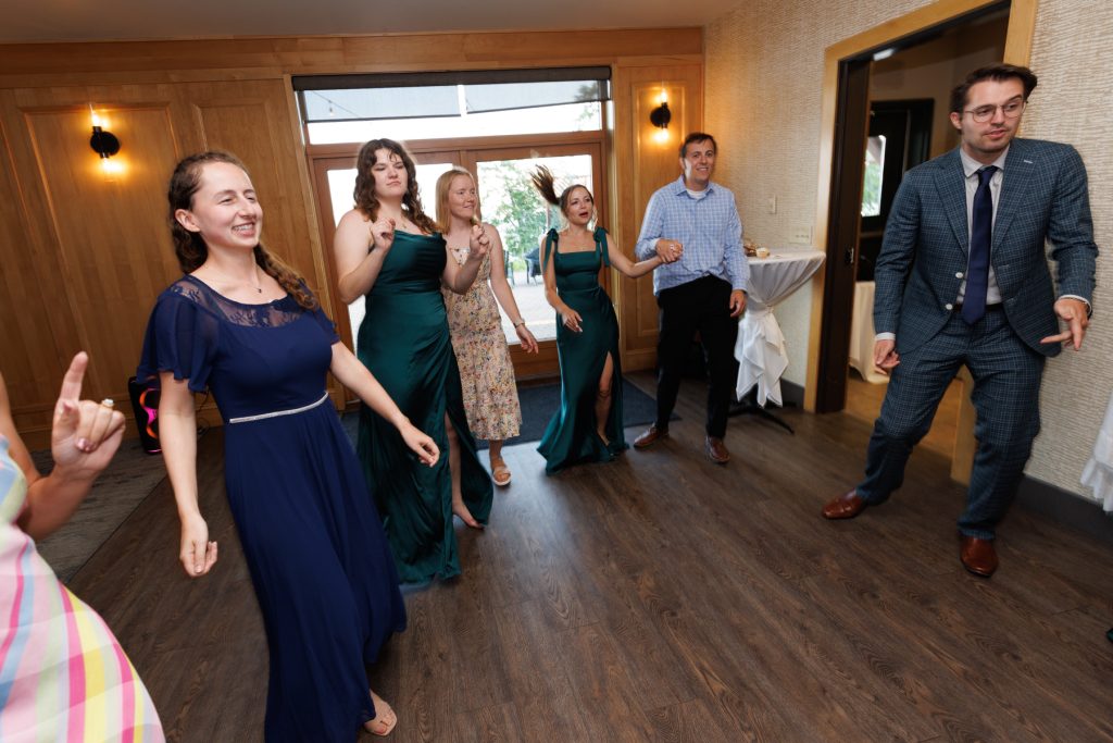 Group of wedding party members joyfully dancing and celebrating at a Wisconsin wedding reception, captured