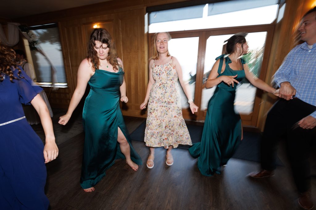 Three bridesmaids and a groomsman dancing together at a Wisconsin wedding reception, showcasing joyful moments