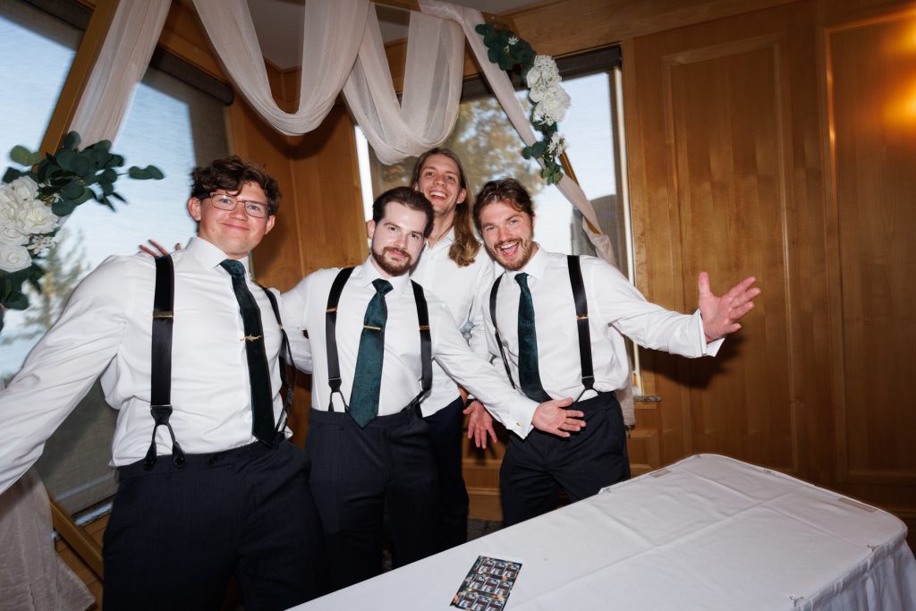 Four groomsmen in suspenders smiling and posing at a Wisconsin wedding ceremony, captured by Beau