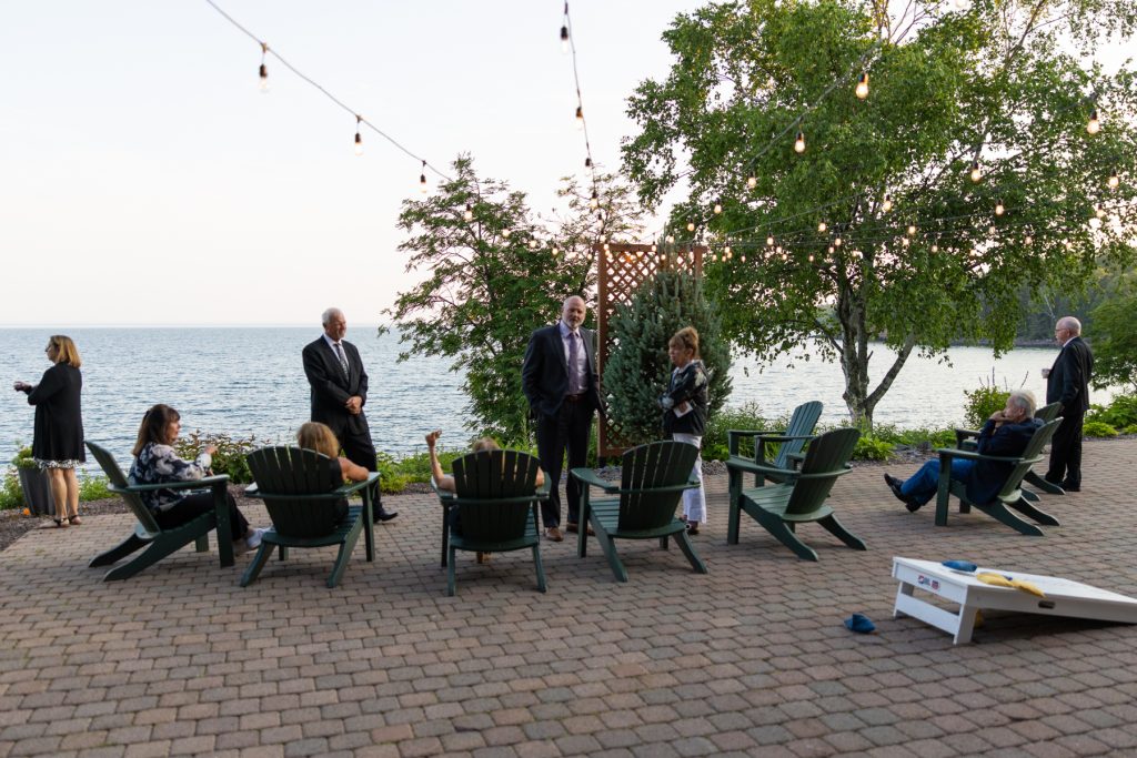 Wisconsin and Minnesota wedding photography captures a lakeside reception scene with guests relaxing in Adirondack