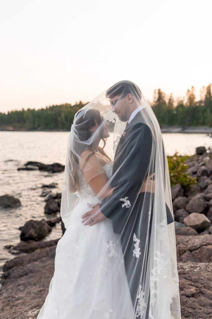 Bride and groom embrace tenderly under a flowing veil, captured during a Wisconsin wedding photography