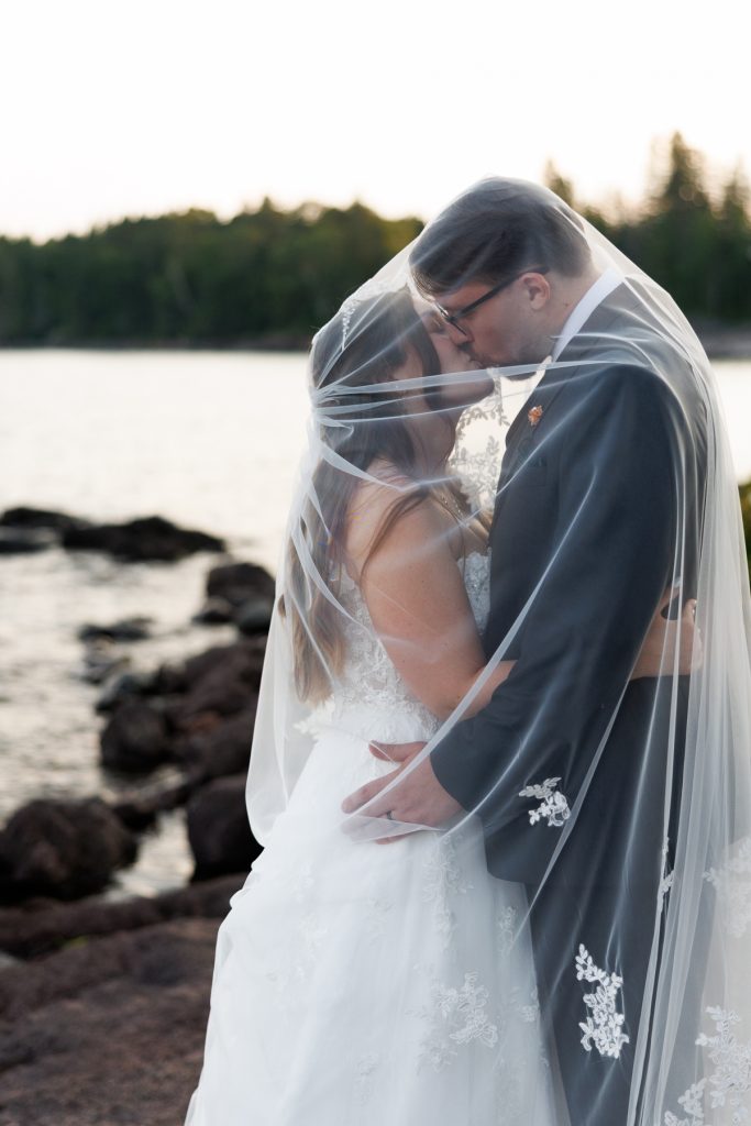 Bride and groom share a romantic kiss enveloped in a flowing veil during a Wisconsin