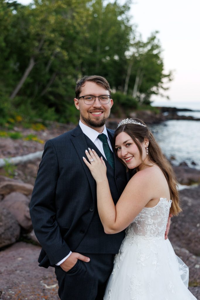 Newly married couple embracing on a rocky North Shore beach in Wisconsin, showcasing wedding photography