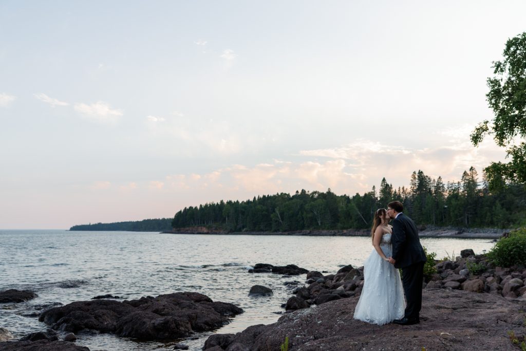 Bride and groom share a romantic kiss on the North Shore of Lake Superior, captured