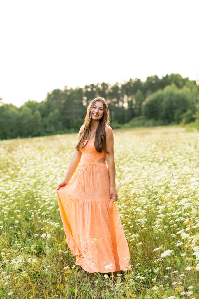 Abby Hayward, a senior from Hayward Wisconsin High School, smiles in a flowing orange dress