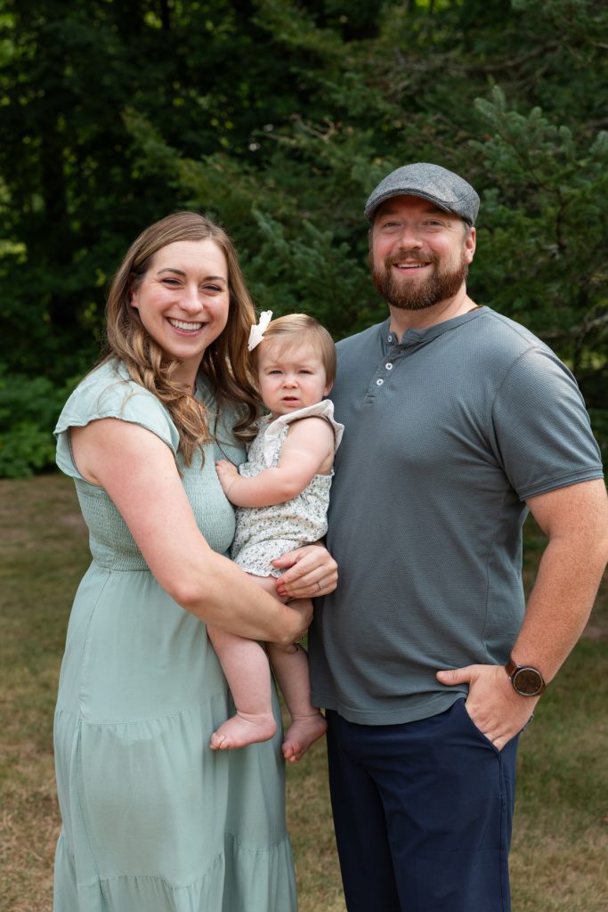 A smiling family portrait of a mom, dad, and baby girl, showcasing a beautiful memory