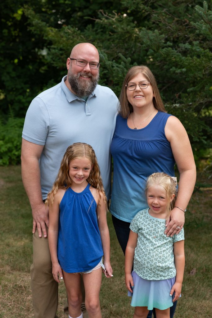 A family portrait showcases a smiling father, mother, and their two young daughters enjoying