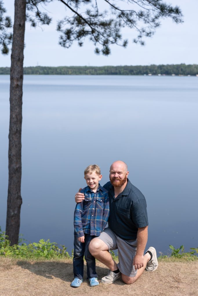 A father and son smile warmly while posing for a family portrait session