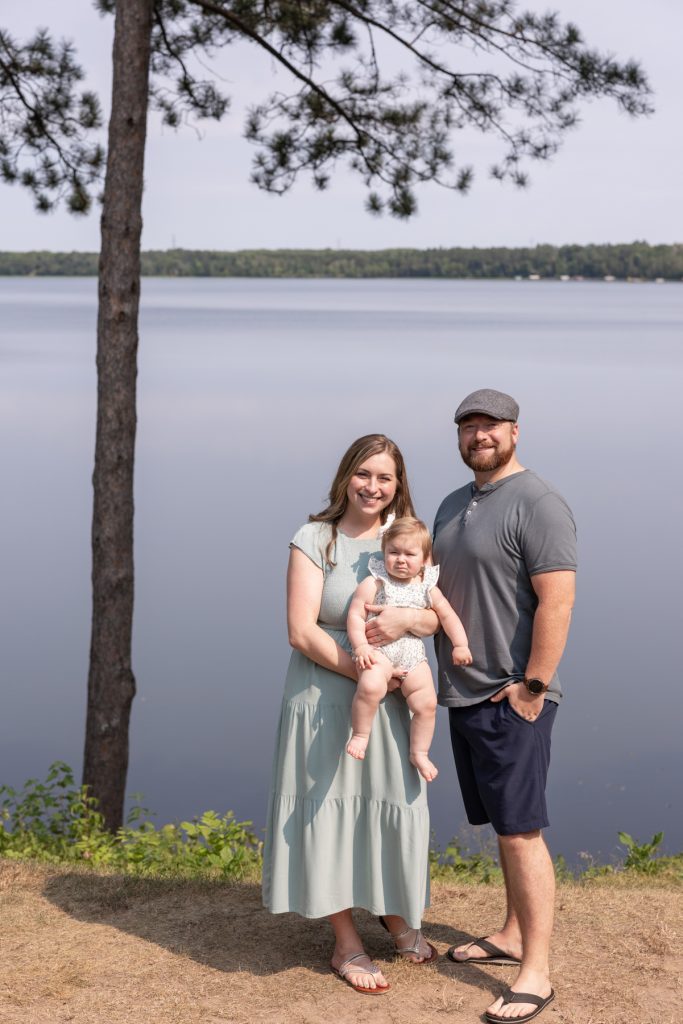 A young family of three—a man, woman, and baby—smiles for a portrait session