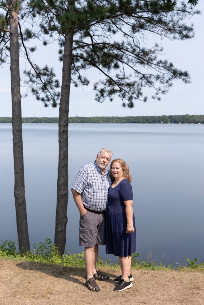 A family portrait session captures a couple standing near a lake in Wisconsin, showcasing memories
