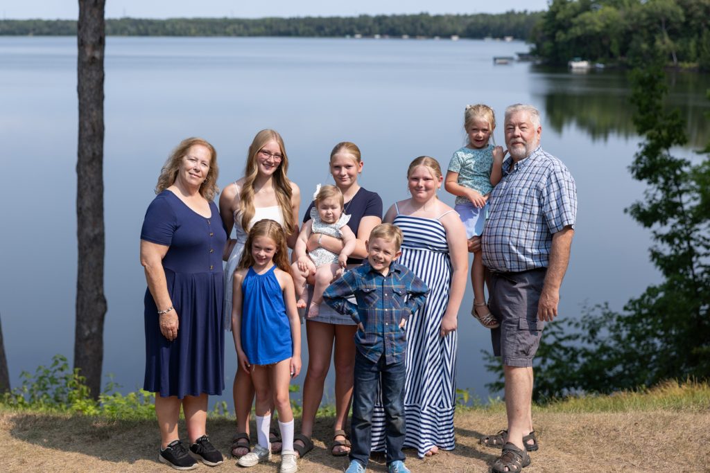 A multigenerational family poses for a portrait session by a serene lake, capturing cherished memories