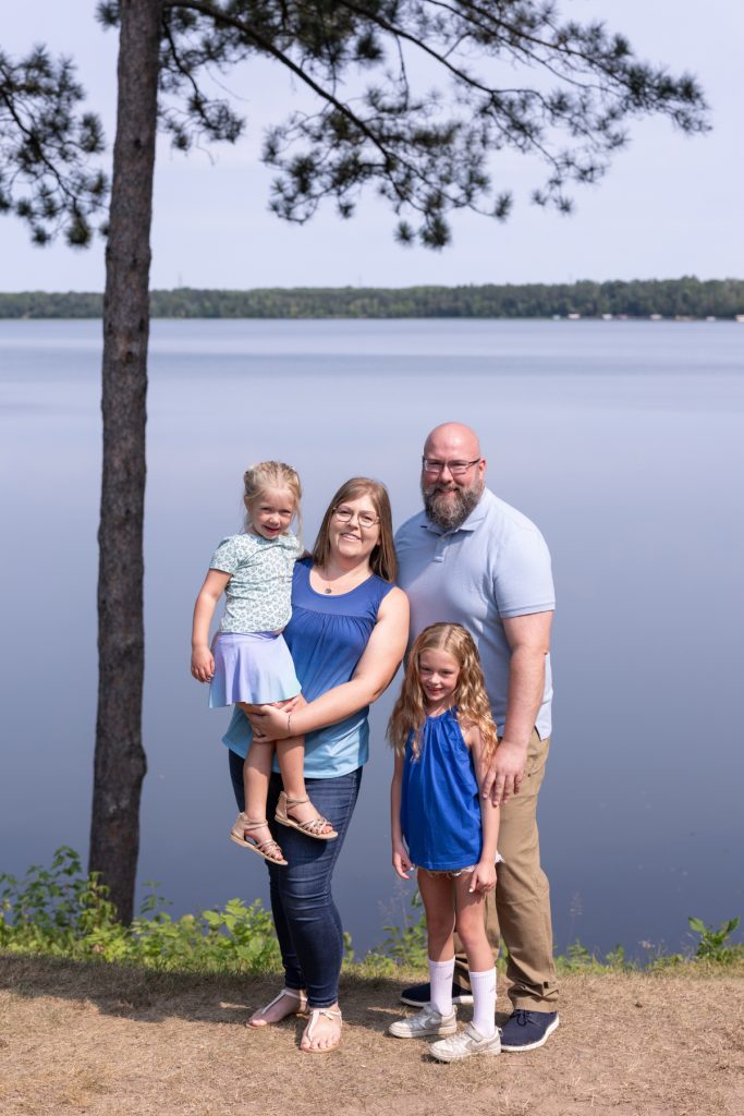 A family of four, including a young girl held by her mother, poses