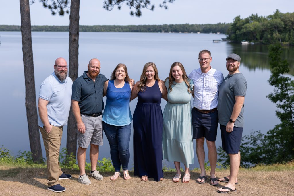 A family of six poses for a portrait session by a lake, capturing cherished memories