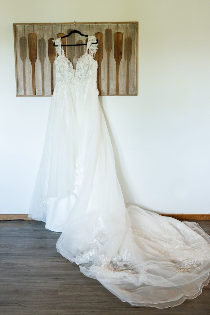 Elegant wedding dress hanging against a backdrop of wooden oars at a Lakewoods Resort wedding
