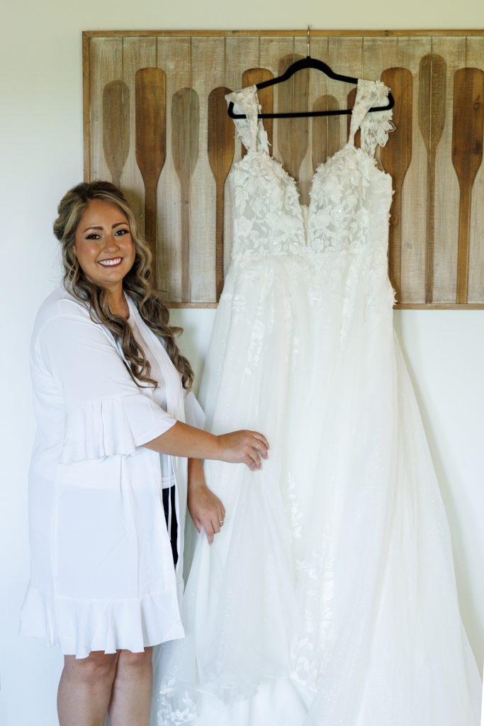 Bride Bianca, photographed by Beau Petersen Photography, smiles beside her stunning wedding dress at Lakewoods