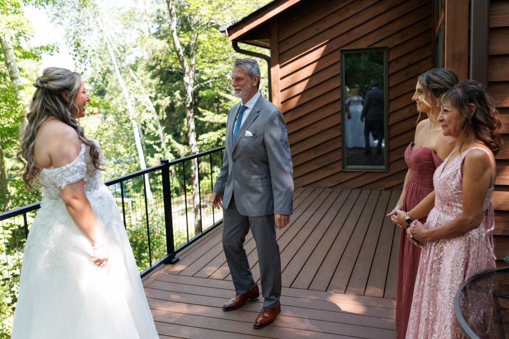 Bride in a wedding gown sharing an emotional first look with her father and mother