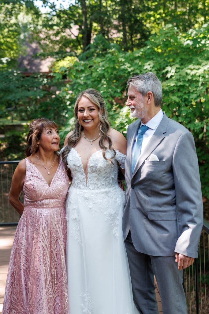Bride Bianca smiles with her parents during her Lakewoods Resort wedding in Cable, Wisconsin, captured