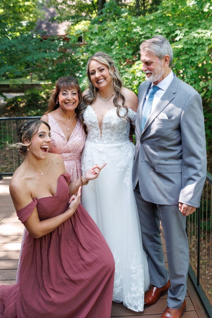 Bianca, the bride in a wedding gown, smiles with her family and bridesmaids at Lakewoods